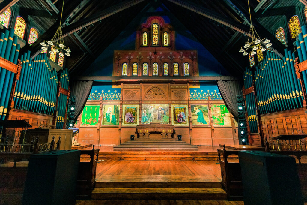 The cathedral, which was formerly the Church of the Epiphany, with 50-foot tall ceiling with arched trusses. An ornate altar and organ surround the room with walls painted in blue and peach.