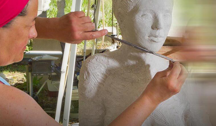 A sculptor precisely measures a clay bust of a figure using calipers.