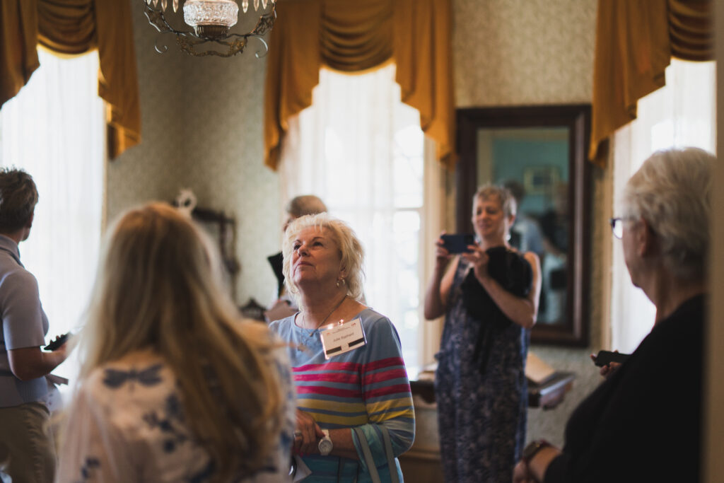 Visitors inside a historic home looking up at furnishings and light fixtures during a tour.