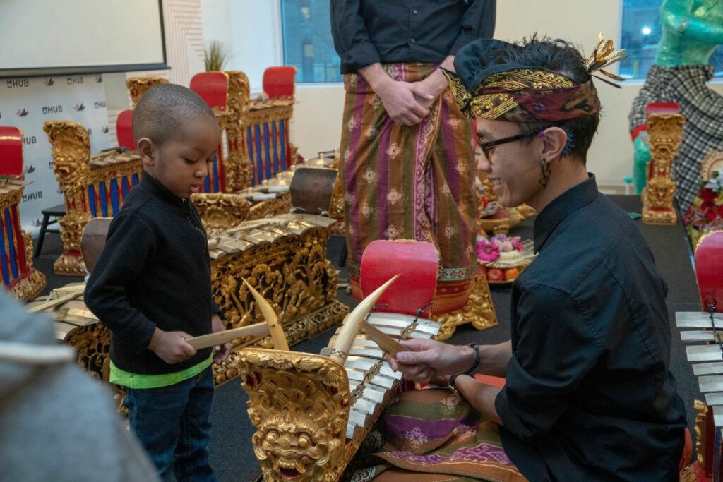A person showing a child how to play a traditional instrument