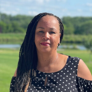 A Black woman with braids posing outside and smiling for the camera