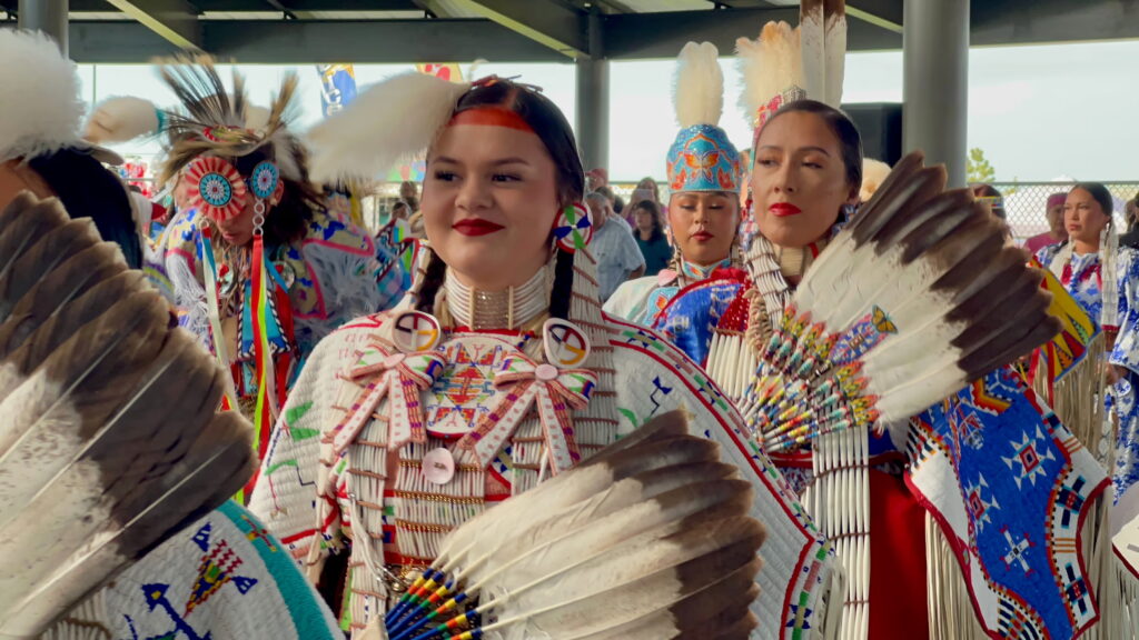 A group of people in traditional Native regalia preparing for a performance.