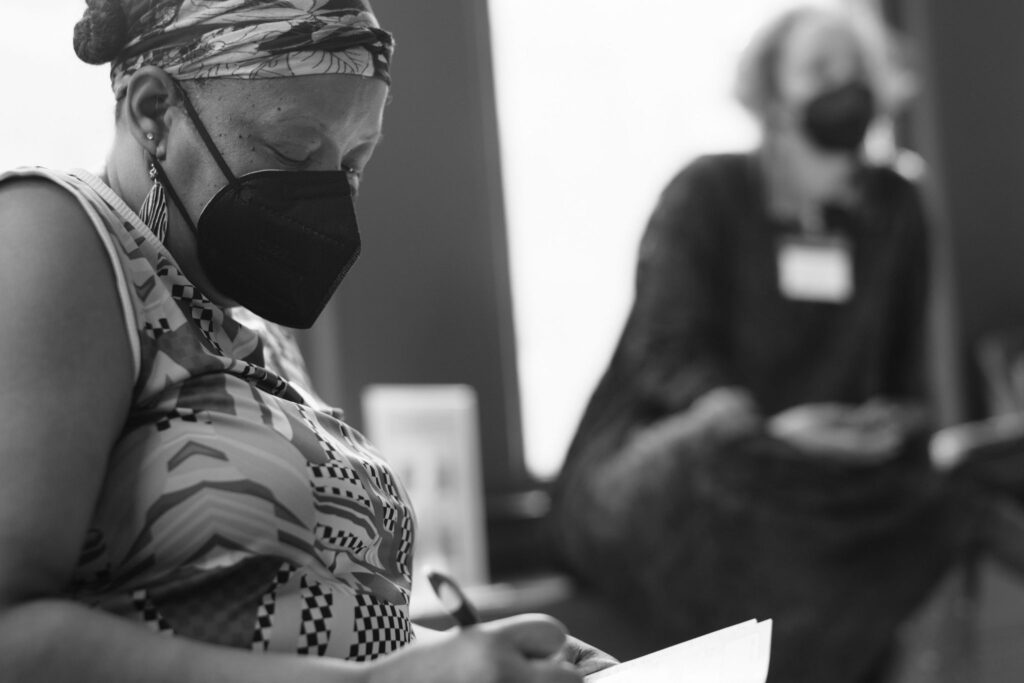 A masked person writing on a sheet of paper.