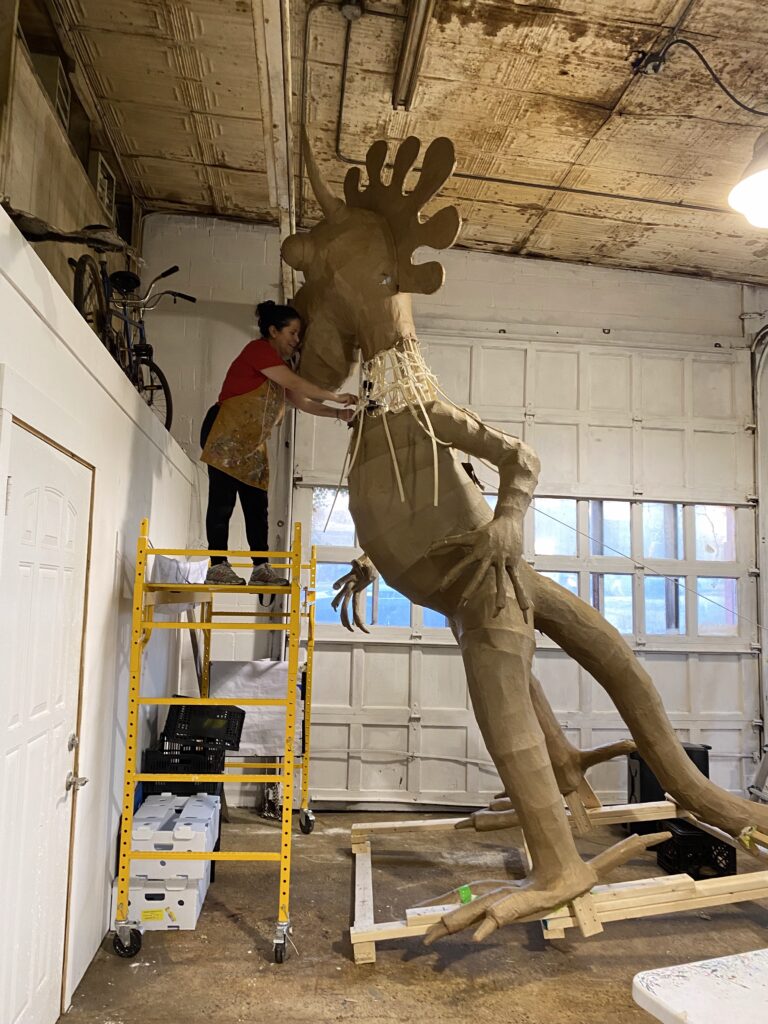 A person standing on scaffolding while working on a large sculpture