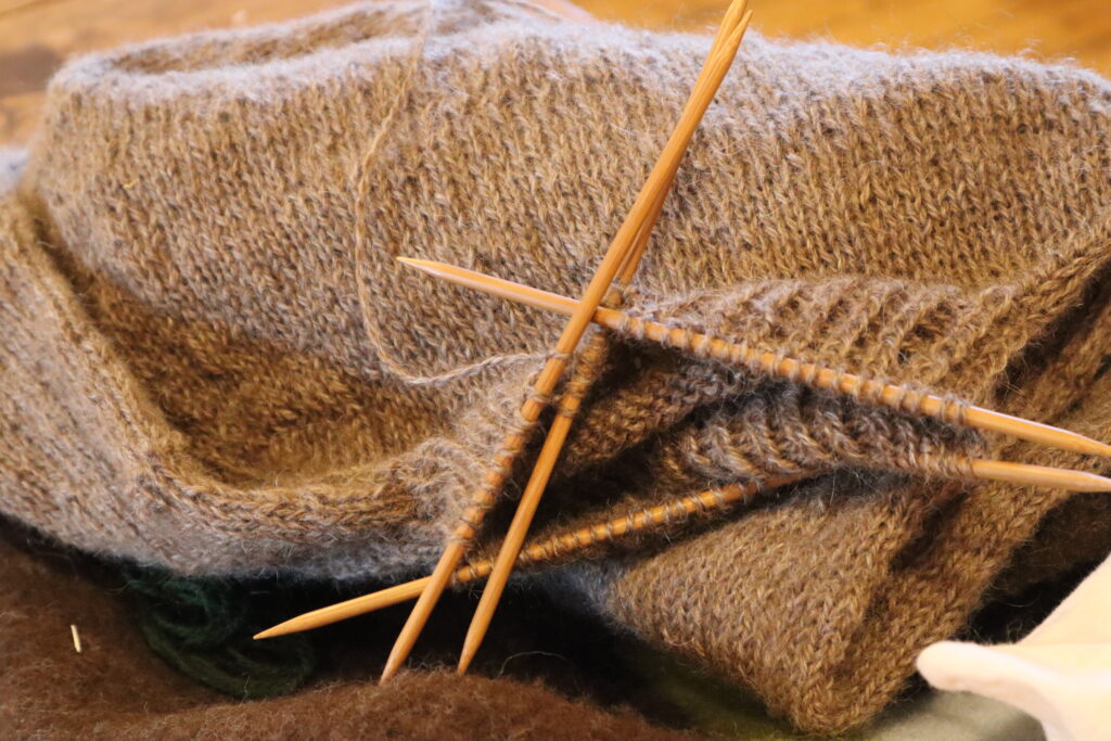 A brown piece of clothing being knitted.