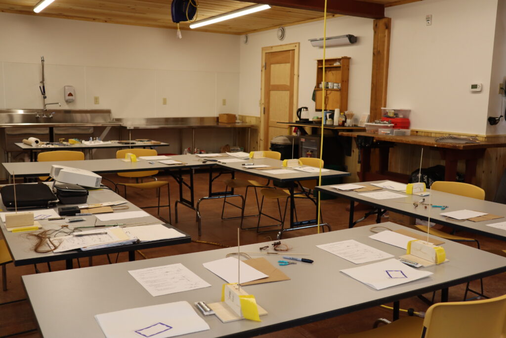 A classroom with tables, chairs, and crafting supplies set up.