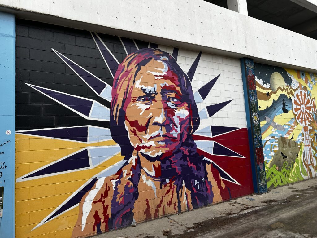 A portrait of Sitting Bull rendered in sunset colors: fuchsia, purple, orange, and yellow.