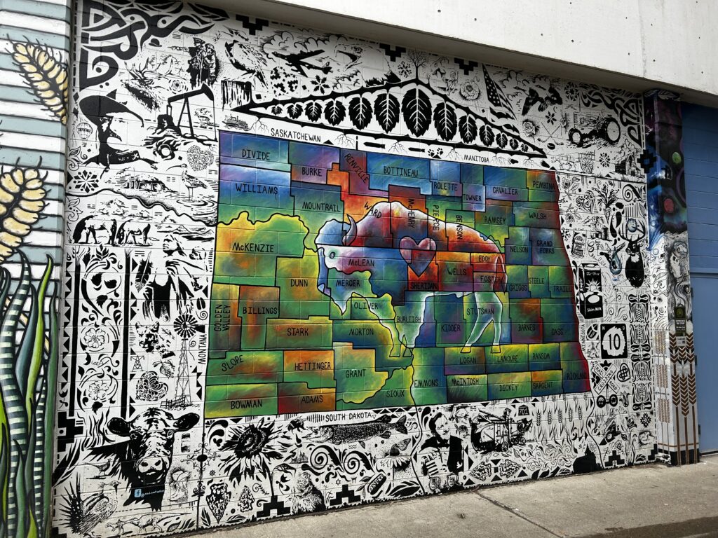 A mural showing a map of North Dakota and all its counties, with a buffalo in the middle and black and white sketches around the outside.