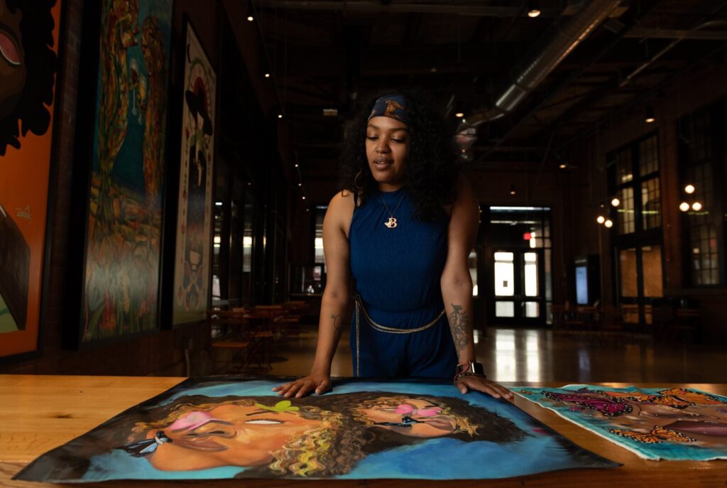 A person standing indoors looking down at a canvas painting.