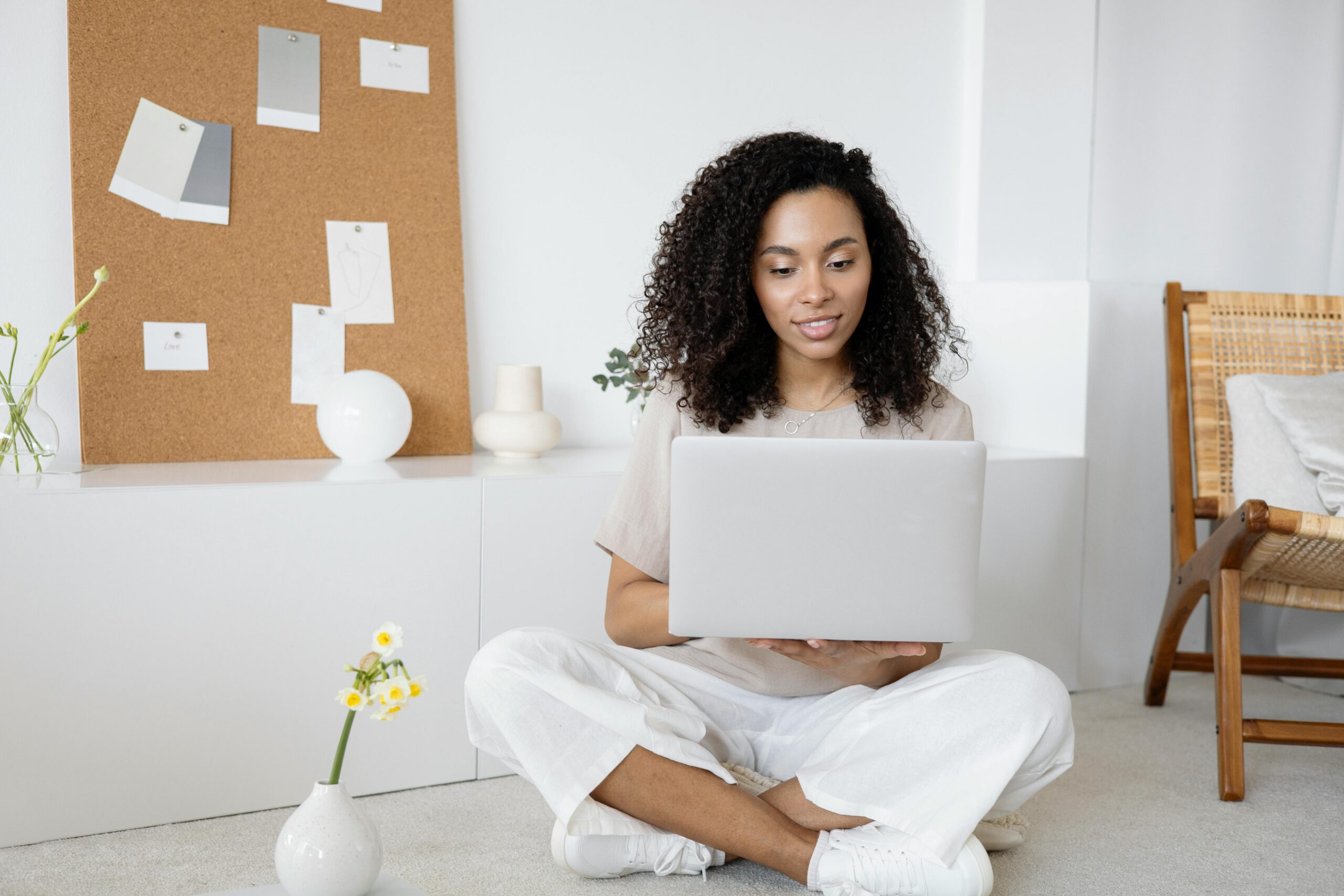 A woman with medium dark skin and curly dark hair scrolls on a laptop