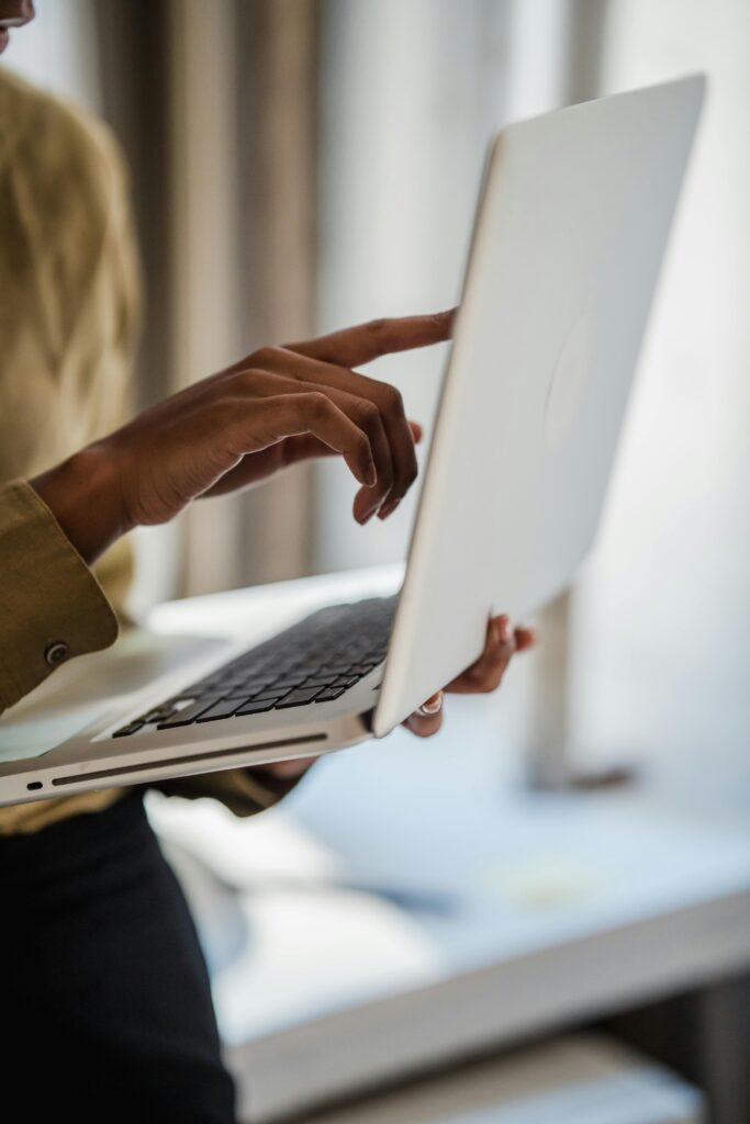 A hand of medium dark skin tone points to a computer