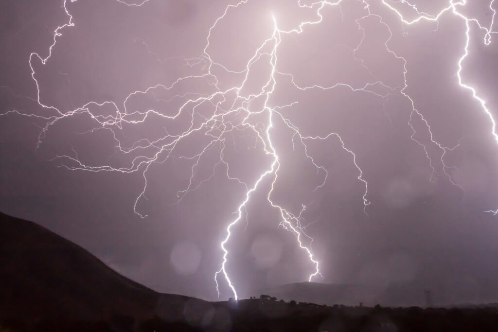 Splintering bolts of white lightning striking the earth against a stormy gray sky.