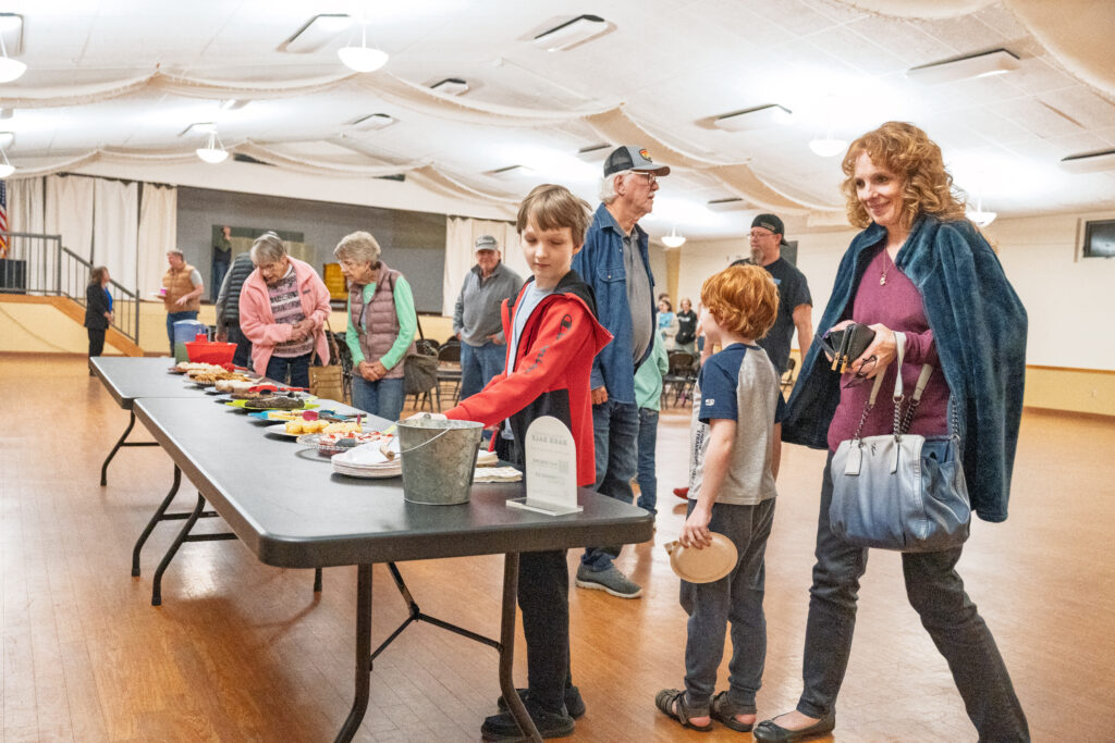 People standing around a dessert table indoors.