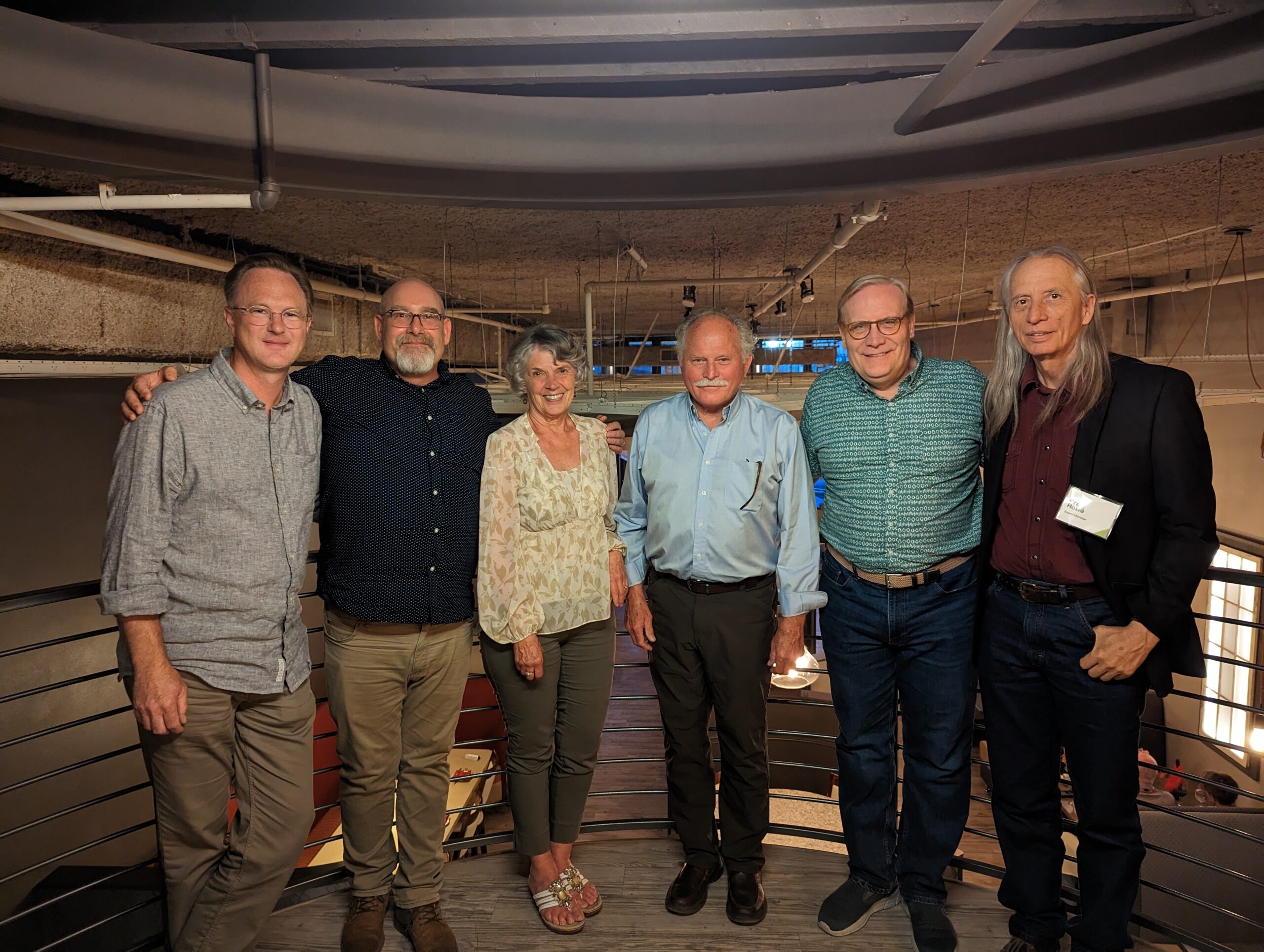 A group of six people pose for a photo in an indoor space.