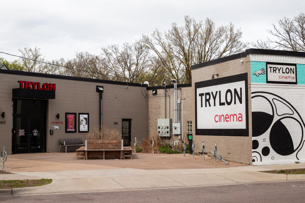 A building courtyard with multiple instances of Trylon Cinema signage and several movie posters.