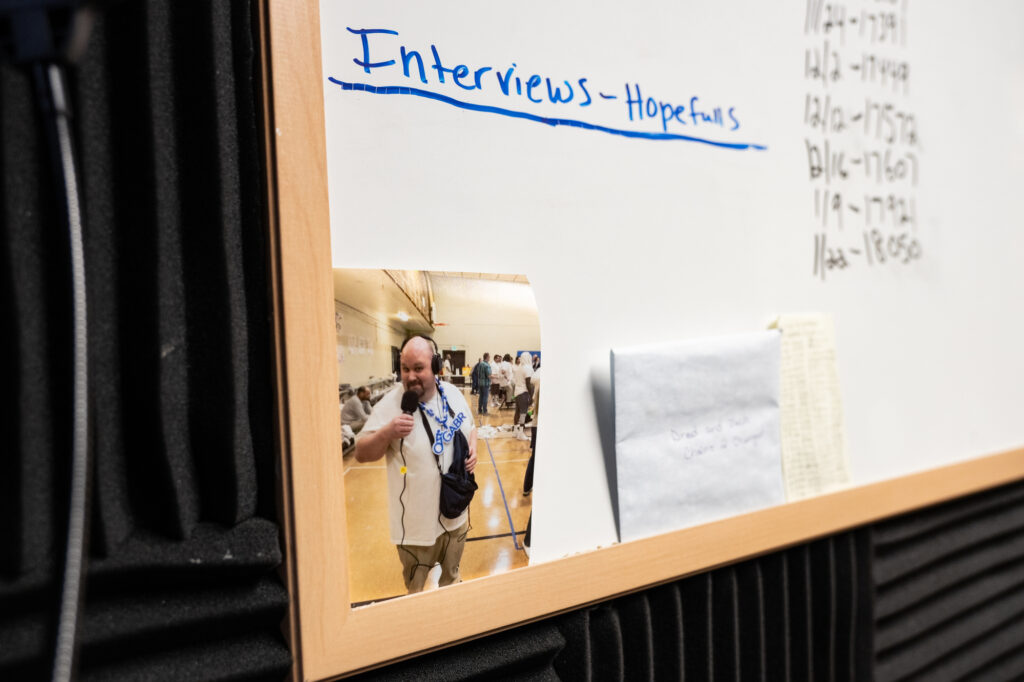 A white board with a photograph of a person holding audio recording gear.