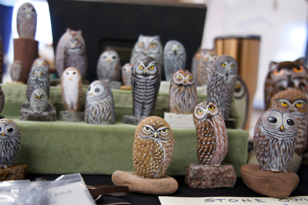 Many painted stone owls displayed on a table.