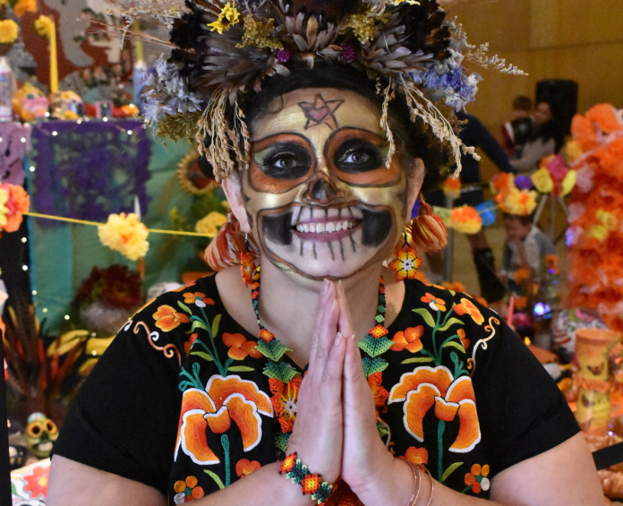 A person in Dia de los Muertos skull makeup and a floral outfit.