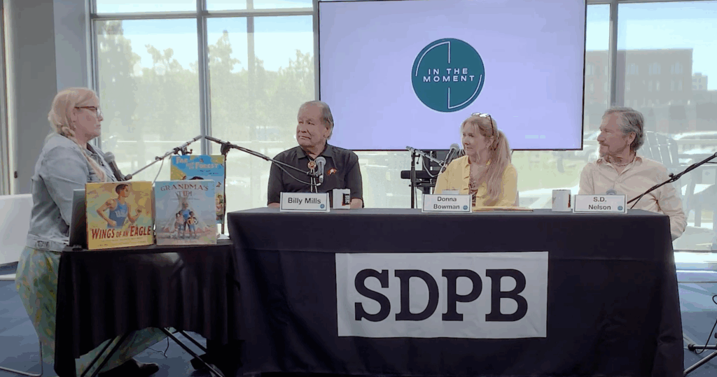 Four seated people at a table with SDPB signage.